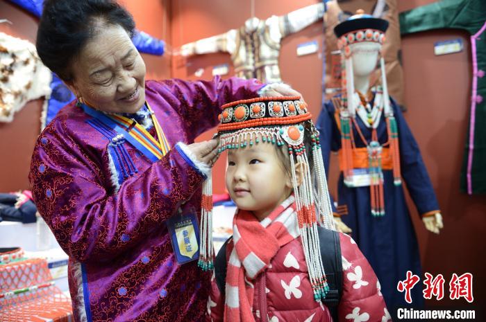 小朋友试戴蒙古族察哈尔部落传统头饰，头饰材质有银、翡翠、珊瑚、玛瑙、珍珠等。　刘文华 摄