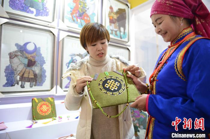 一位女士咨询羊毛毡制作的蒙古族时尚挎包。　刘文华 摄
